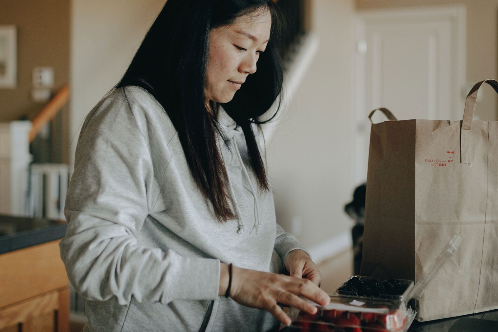 A woman looking down while shopping, holding a paper bag